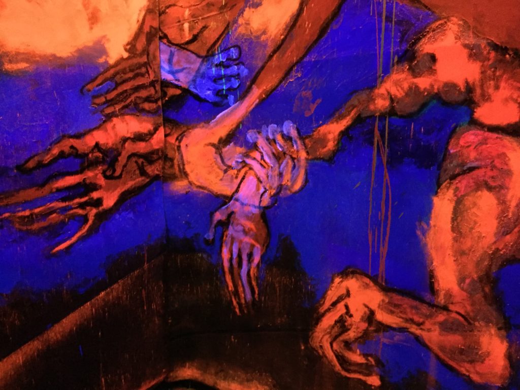 mains et pieds osseux en peinture orange fluorescente sur fond bleu intense fluo