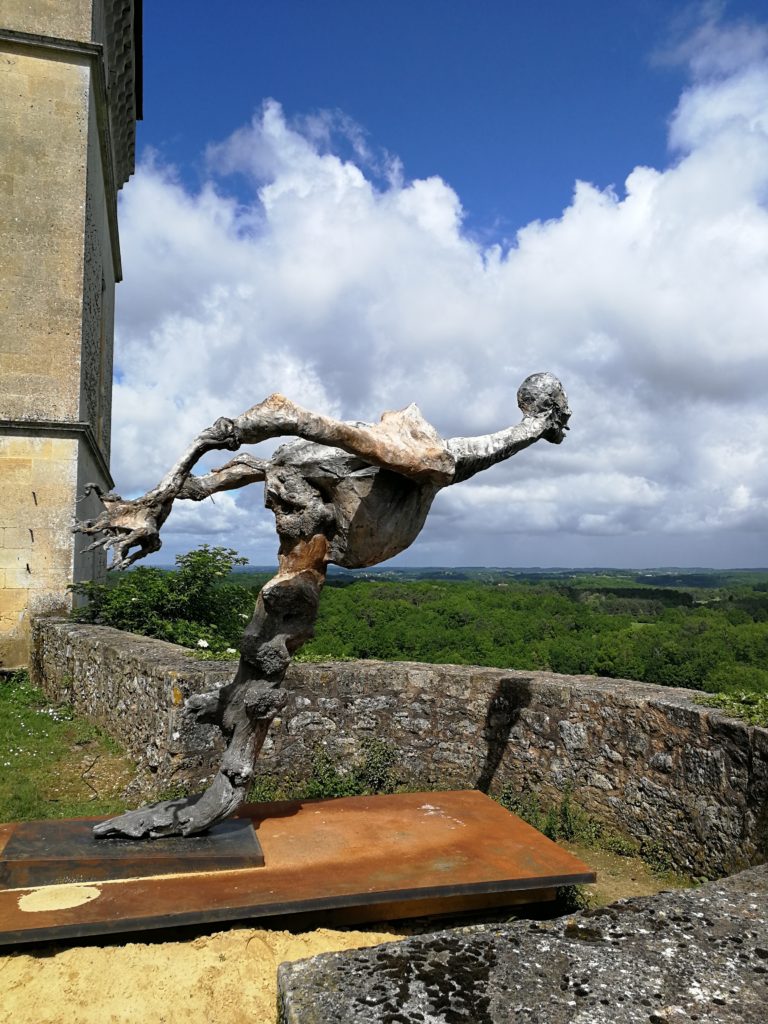 scultpture en ciment et ceps de vigne, créateure plongeant vers l'horizon