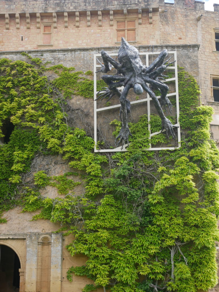 araignée en bronze installée sur le mur du château parmi la végétation