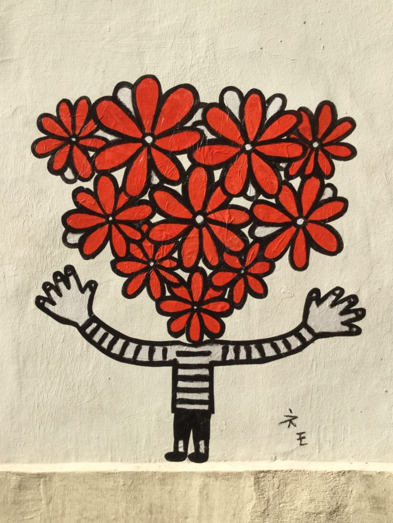 petit personnage aux longs bras en mariniière blancehe et noir avec un bouquet de fleurs rouges à la place de la tête de Megumi Nemo