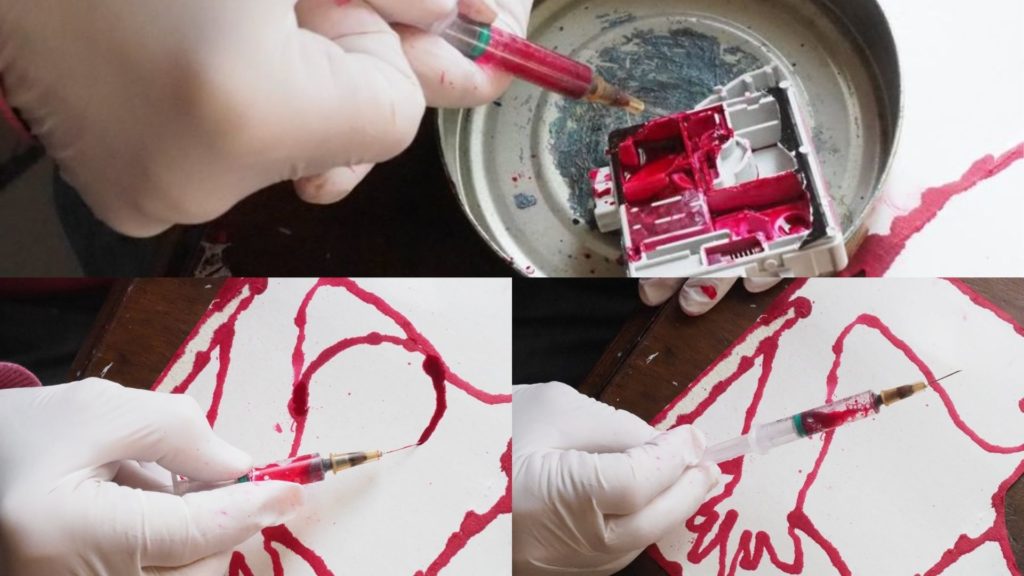 cartouche d'encre rouge pour imprimante récupérée à la seringue et mains qui réalisent un dessin à la seringue