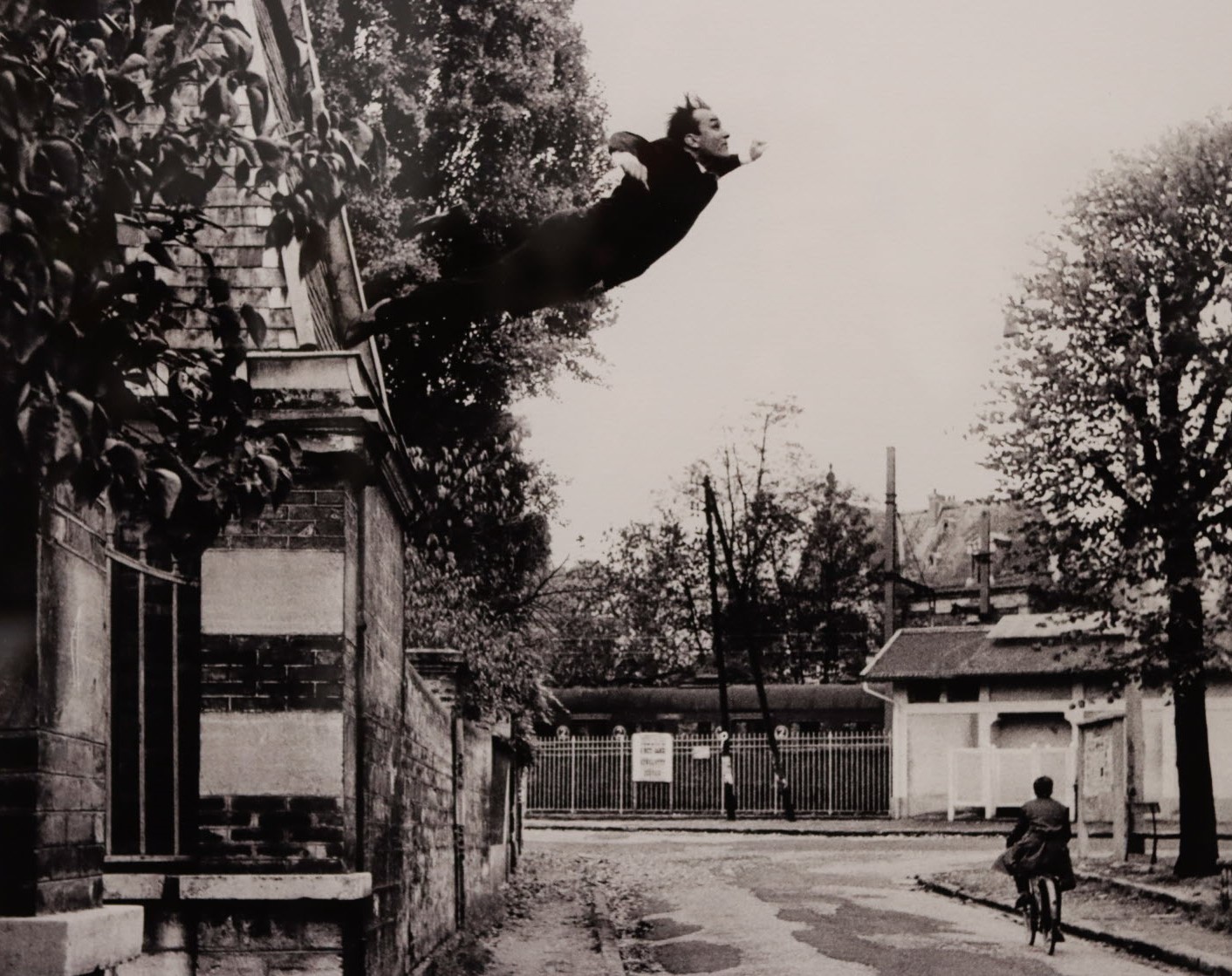 photo en noir et blanc d'une rue vide, un piéton au loin et un homme qui plonge d'un mur au premier plan