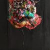 Image qui représente une tête en sculpture textile peinte aux diverses techniques , sur une tige en métal et un socle en bois peint en noir