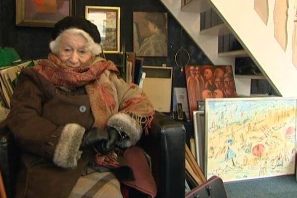 image qui représente une femme âgée élégante vêtue d'un manteau à manchons de fourrure, d'une étole au motif cachemire et d'une toque de fourrure noire sur la tête