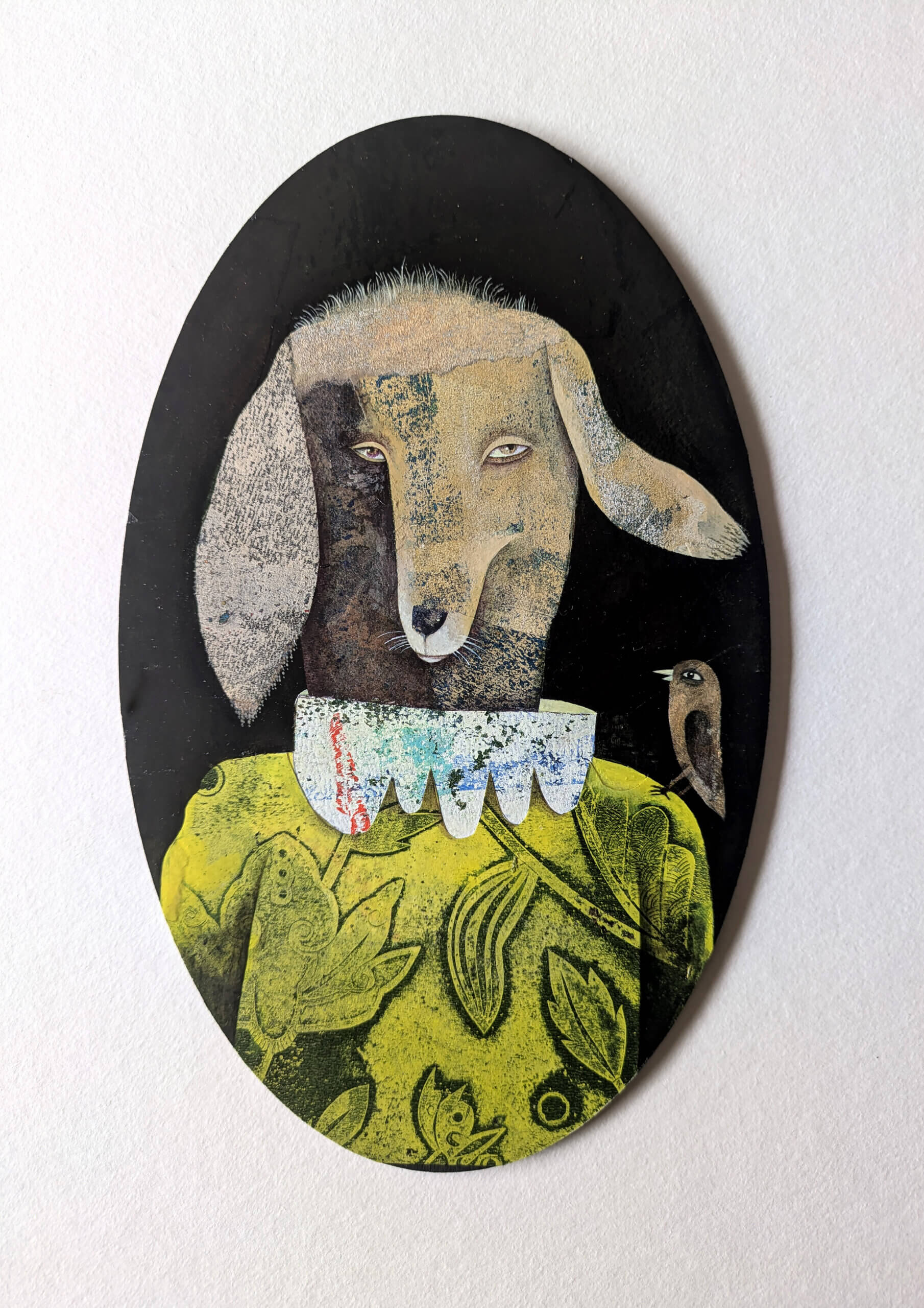 photographie qui représente une oeuvre médaillon portrait d'animal costumé de l'illustratrice Vanessa Hié : Chien avec oiseau sur l'épaule 21 x 13 cm