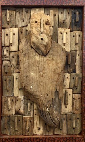 oeuvre en bois flottés de Marc Bourlier représentant un homme solitaire devant un ensemble de visages, cadre dessiné de visages